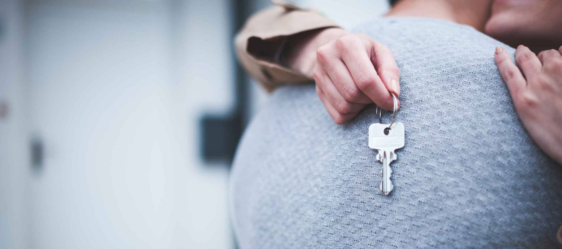 Young woman holding keys hugging husband