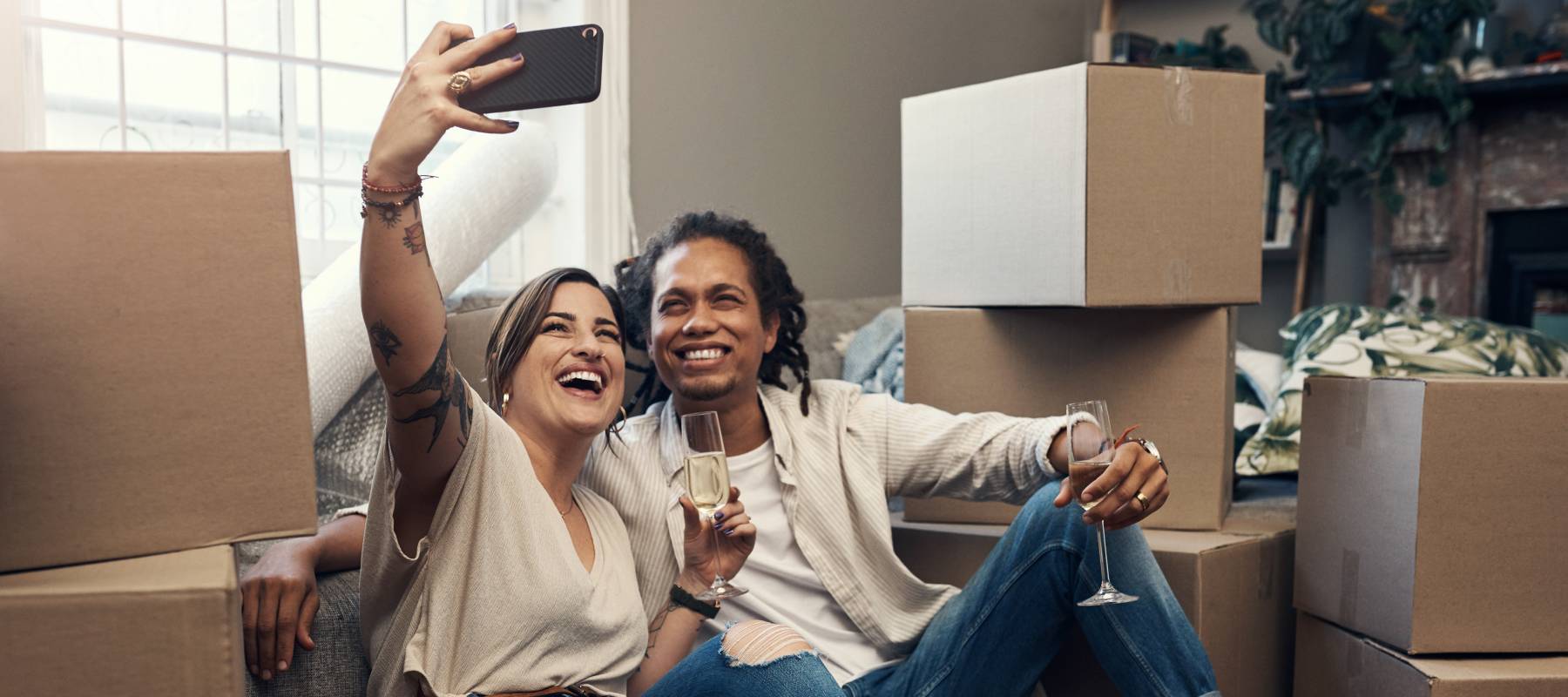young biracial couple taking a selfie while busy moving into their new home