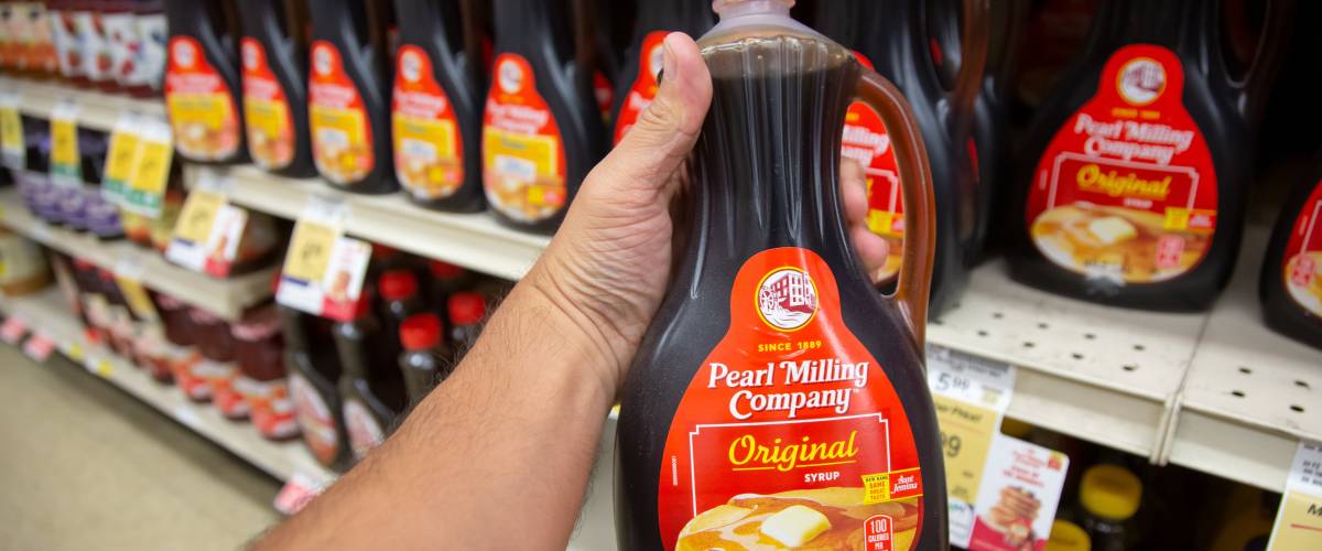 a person holding a bottle of Pearl Milling Syrup in their hand