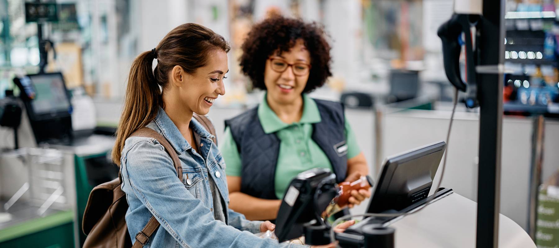An employee helps a woman at checkout.
