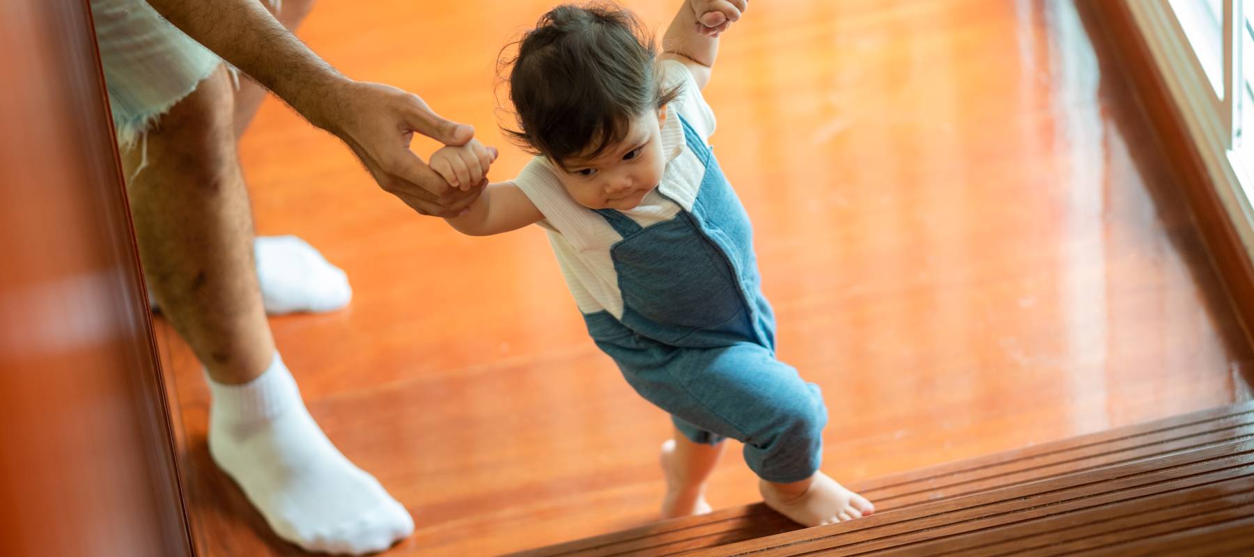 Toddler gets boosted up the stairs by parent.