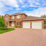 Red brick house with red driveway leading up to home