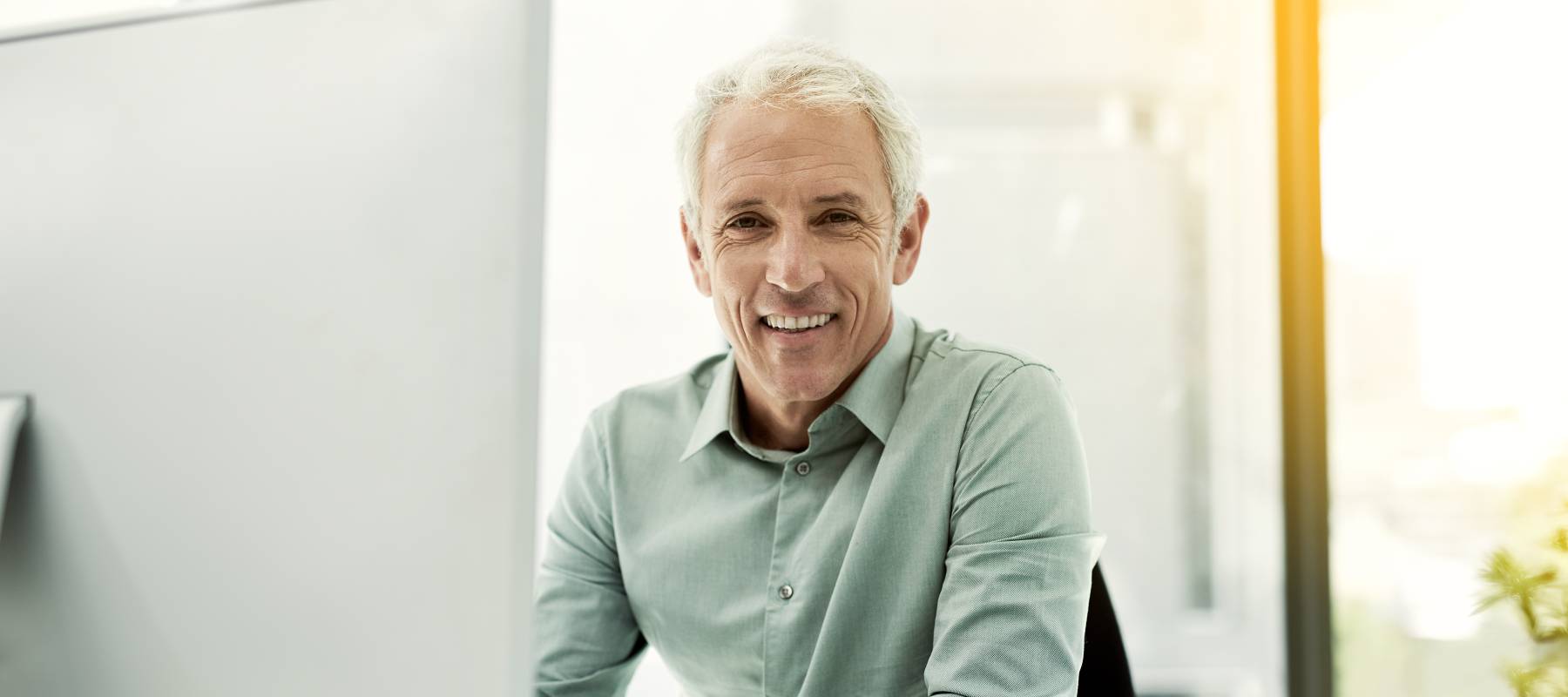 a Caucasian man in his 50s in an office environment, smiling at the camera