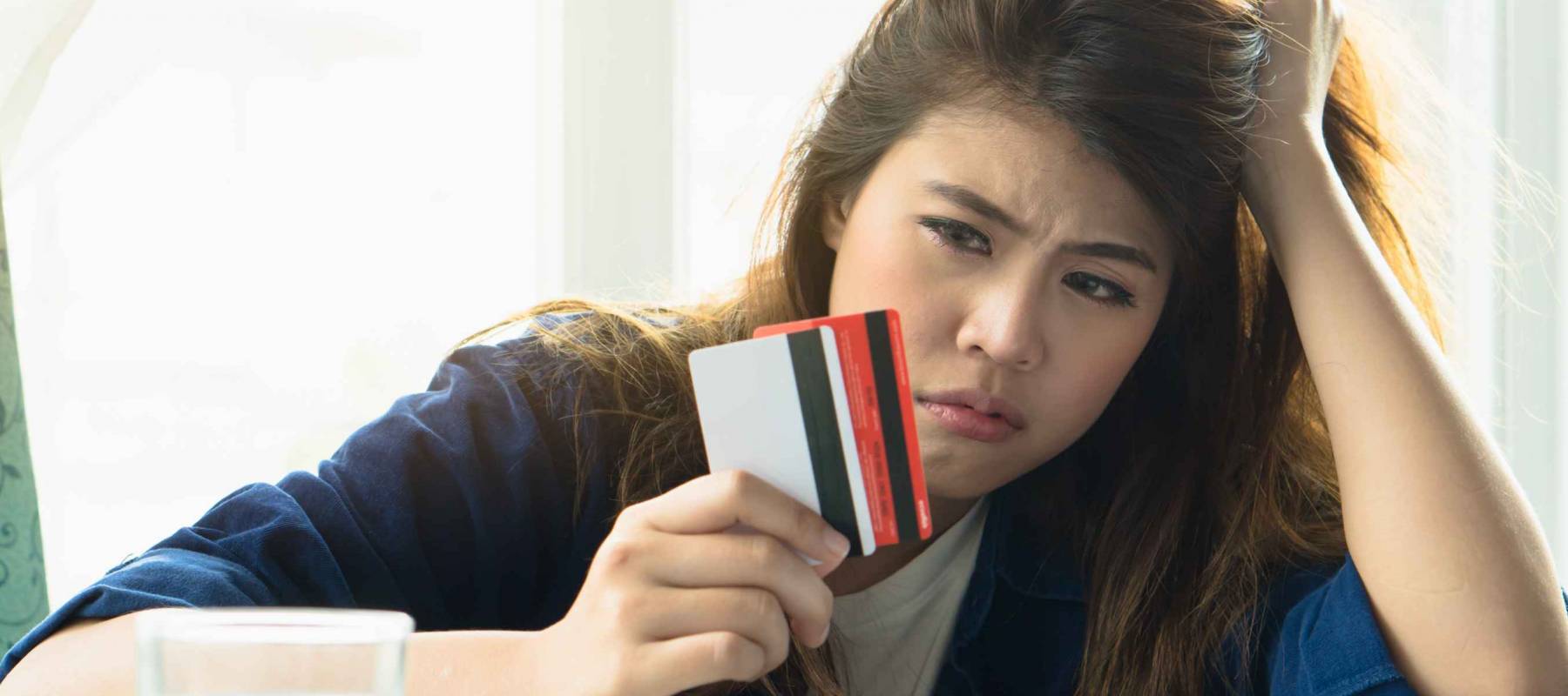 stressed young asian woman trying to find money to pay credit card debt.