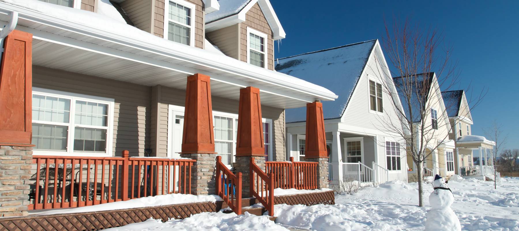 Houses covered with snow with snowman in front yard