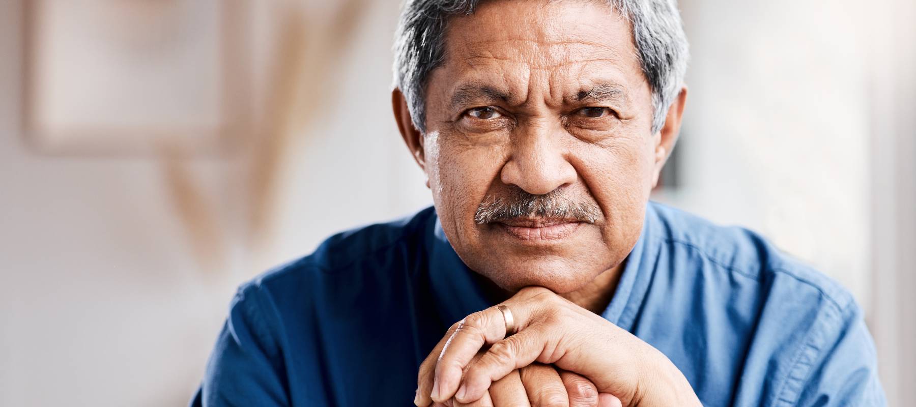senior Middle-Eastern man leaning in his walking stick at home