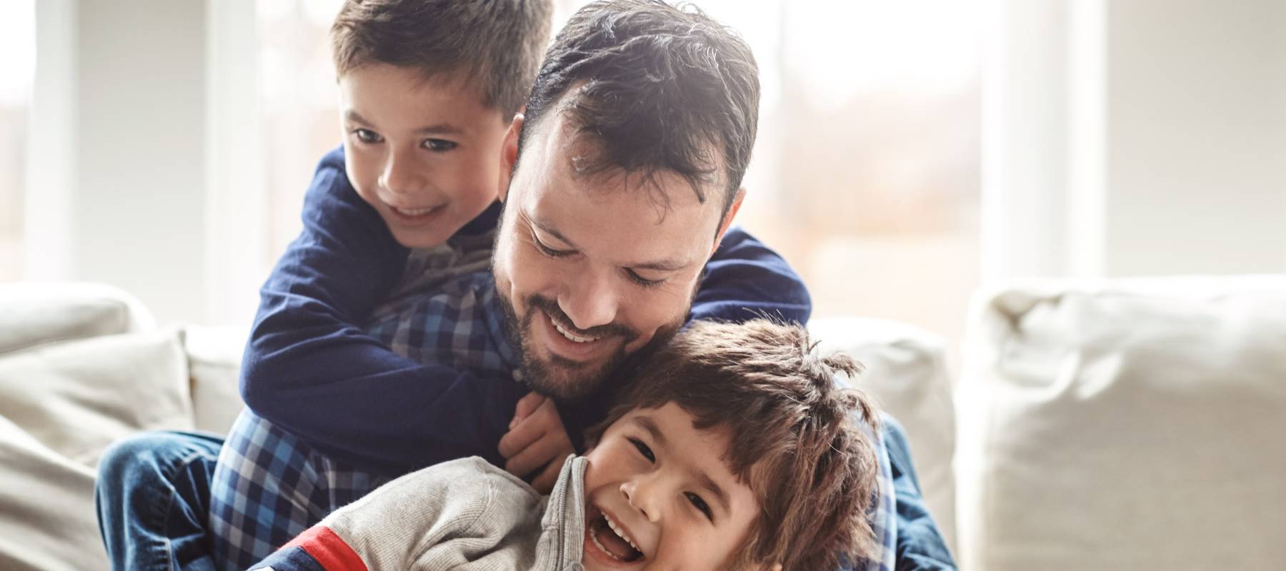 Caucasian single fad with his two sons laughing on the couch at home