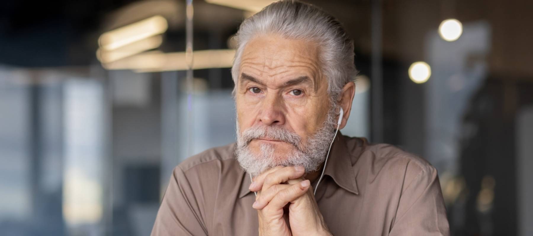 a senior Caucasian man staring at the camera with a serious expression in a workplace environment