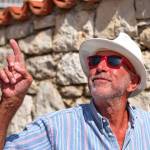 Waist up portrait of a senior man with a hat against the stone wall