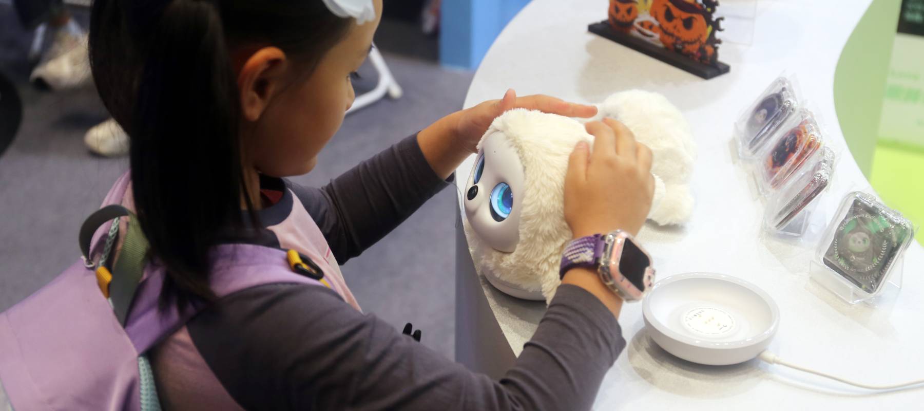 A child plays with AI pet robot toy Ropet at a tech convention in Shanghai, China, Oct. 27, 2025.