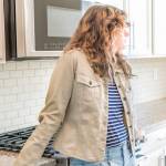 One young woman standing in kitchen in clean, modern, white home design before move-in