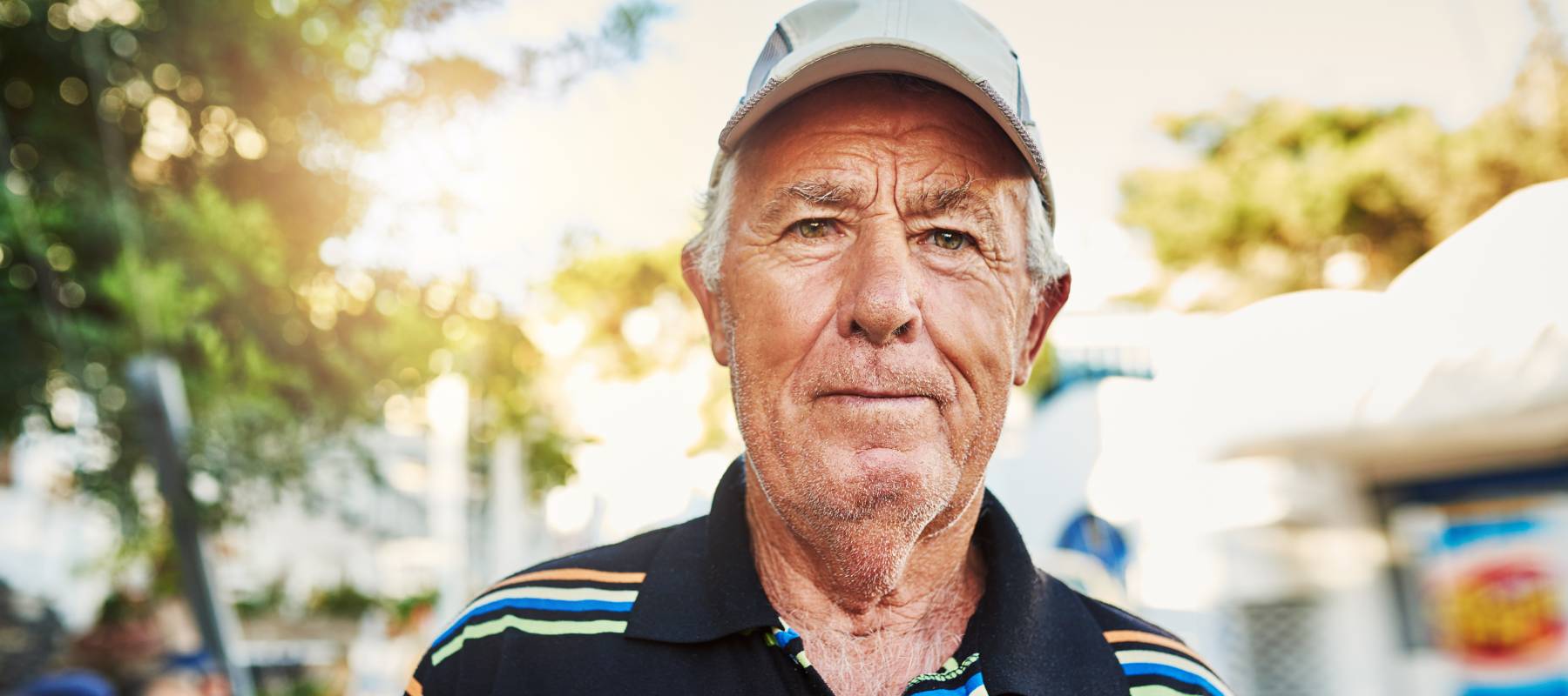 a senior Caucasian man looking at the camera while outdoors