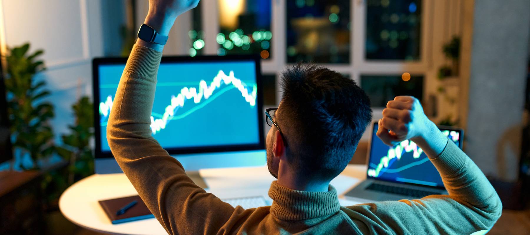 the back of a man's head as he looks at investments on laptop screen