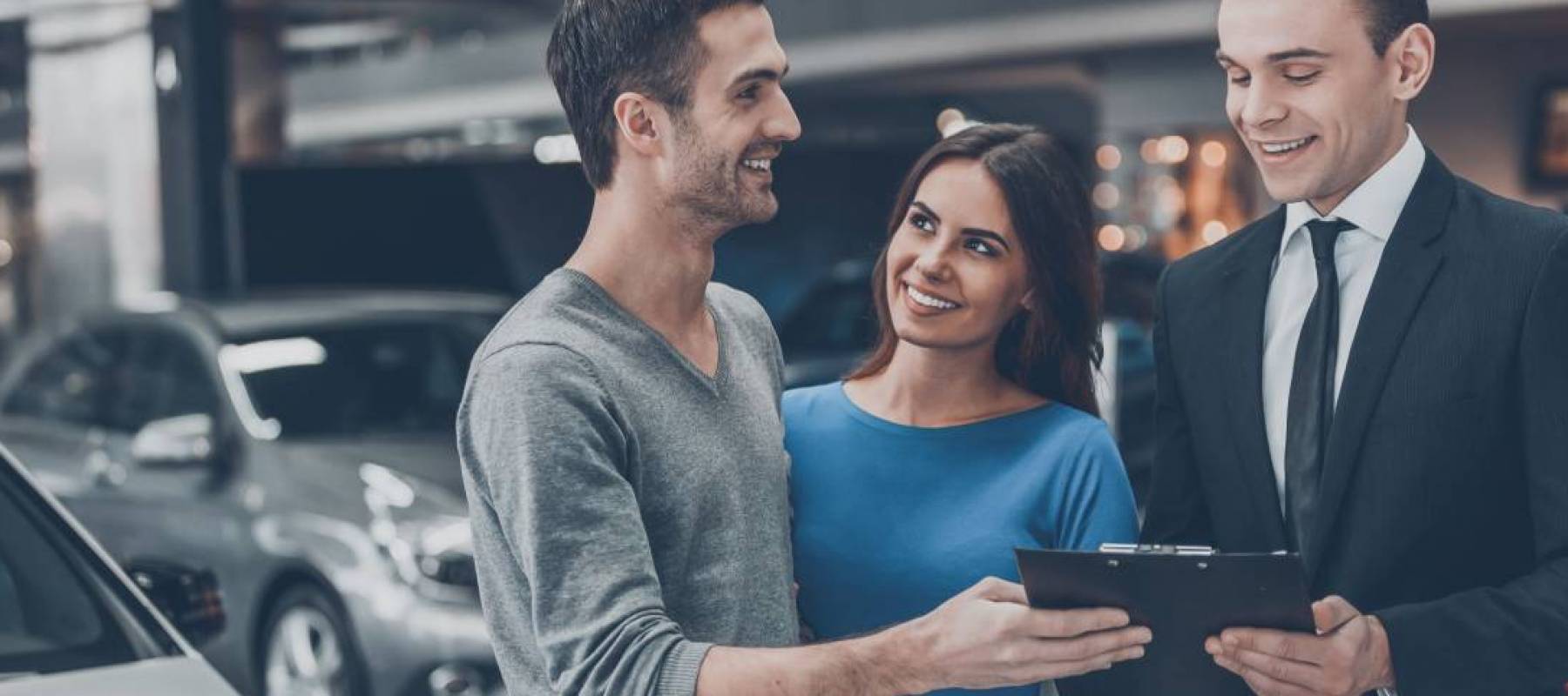 Young car salesman making deal with young couple