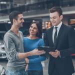 Young car salesman making deal with young couple