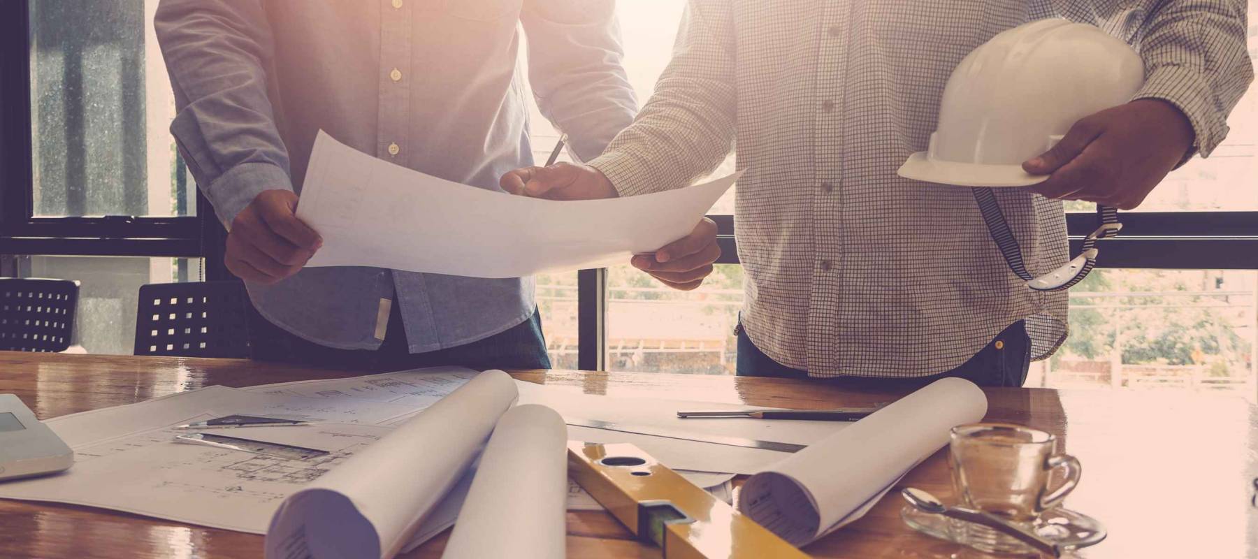 Architects working with blueprints in the office, holding hard hat