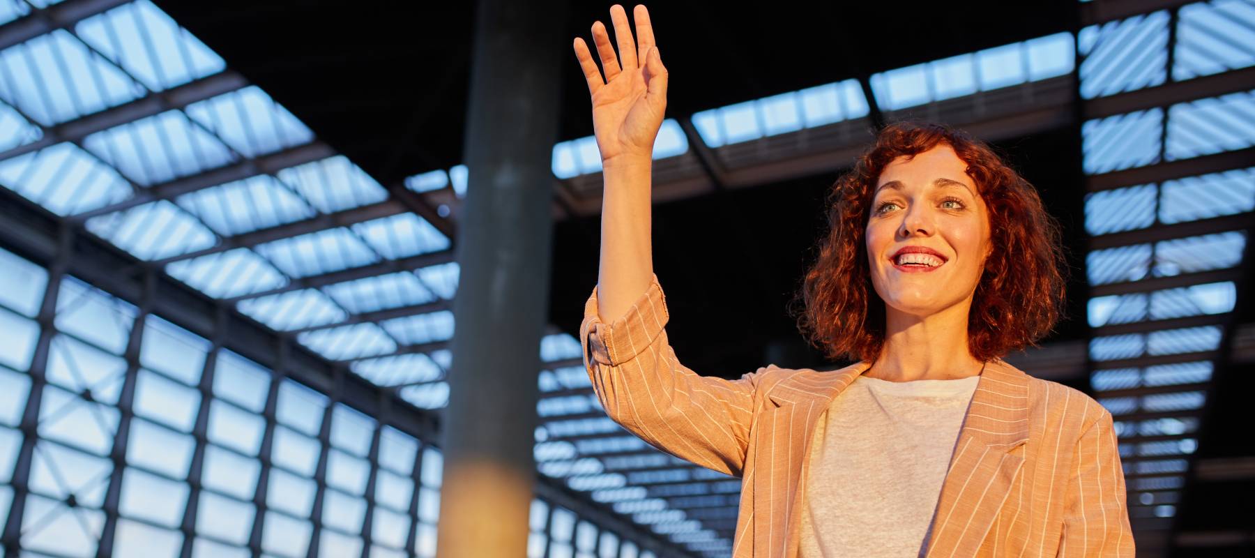 A woman waves goodbye at a train station.