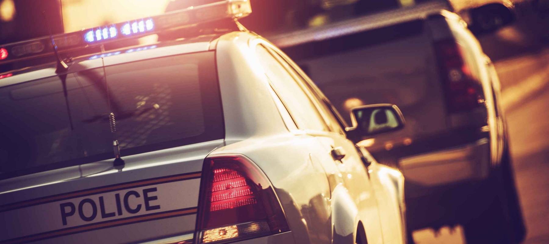 Police car with lights on pulls over truck