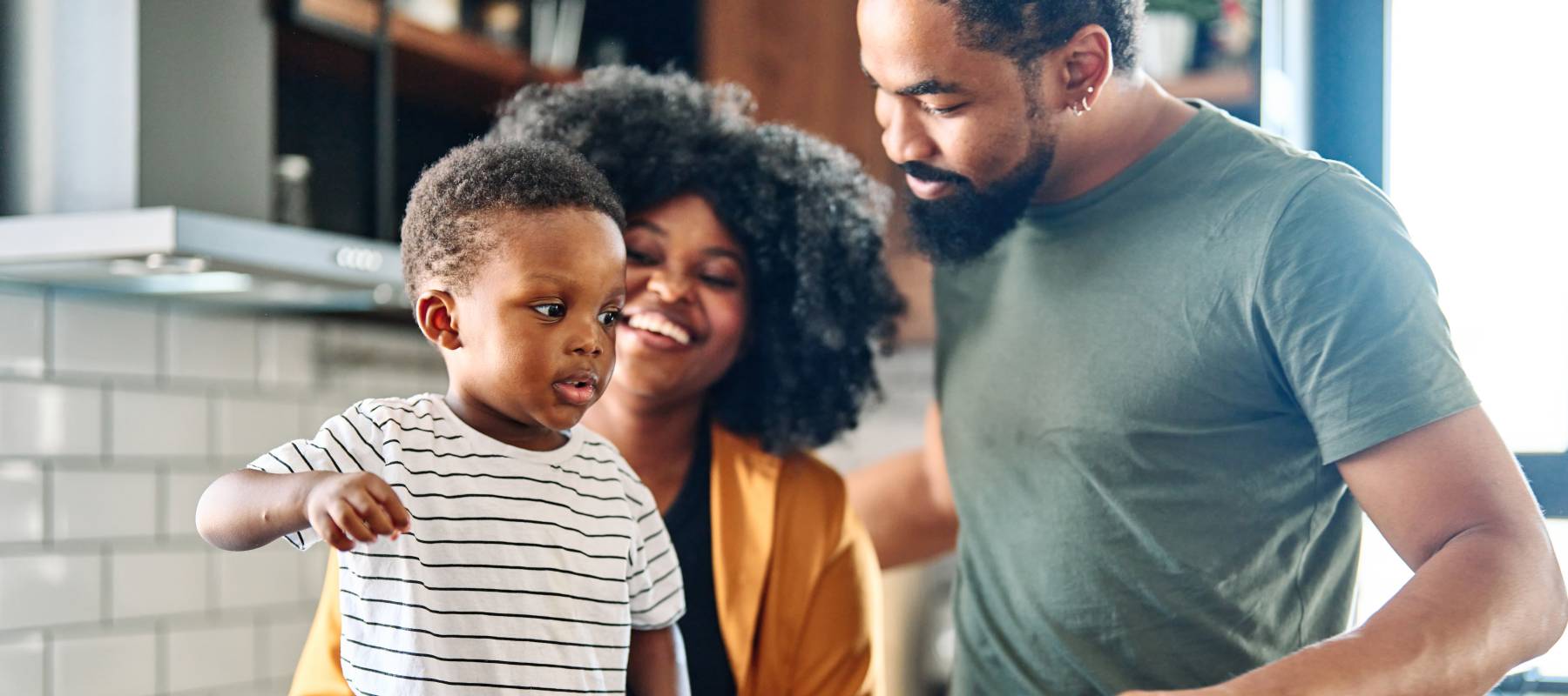 two Black adults with a young toddler in the kitchen