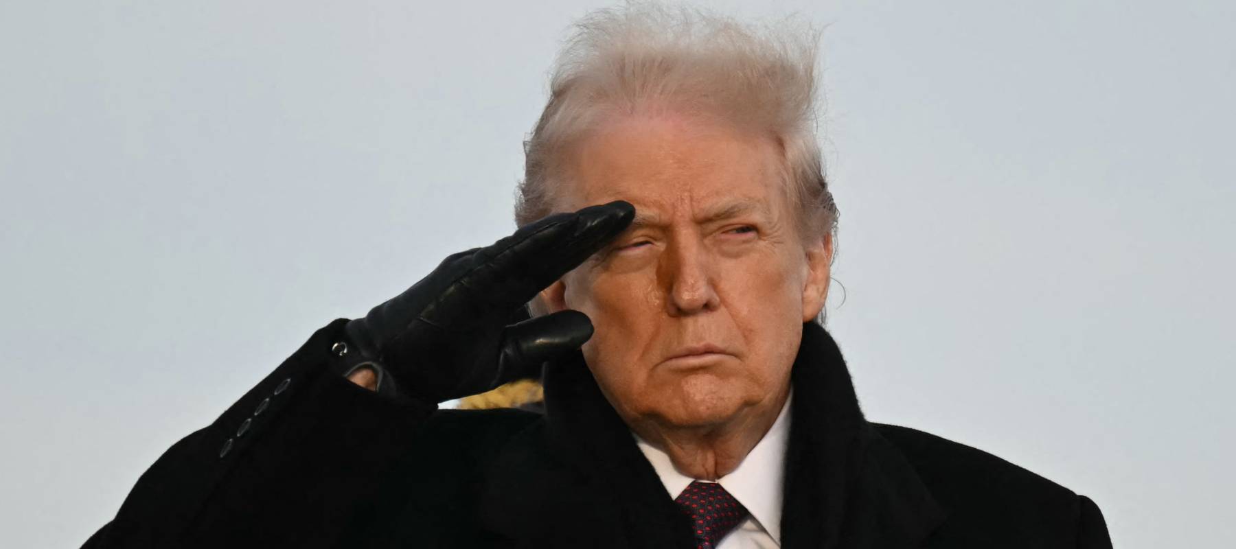US President Donald Trump salutes as he observes the return of the remains of two Iowa National Guard members on December 17, 2025..