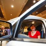 A woman sits in a car at a dealership.
