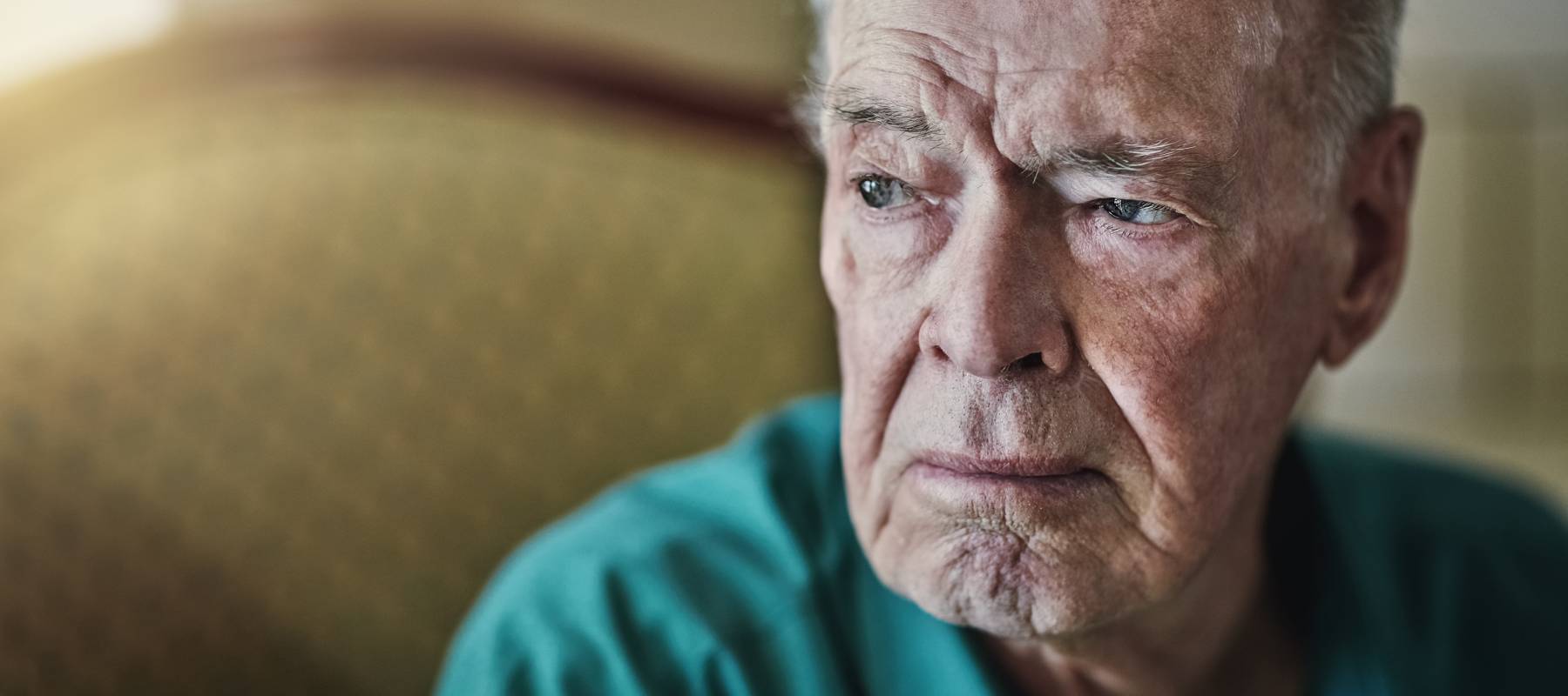 sad senior Caucasian man looking outside window