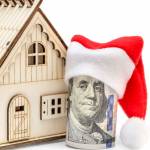 Santa's hat on rolled money and  model of house. Isolated on white.