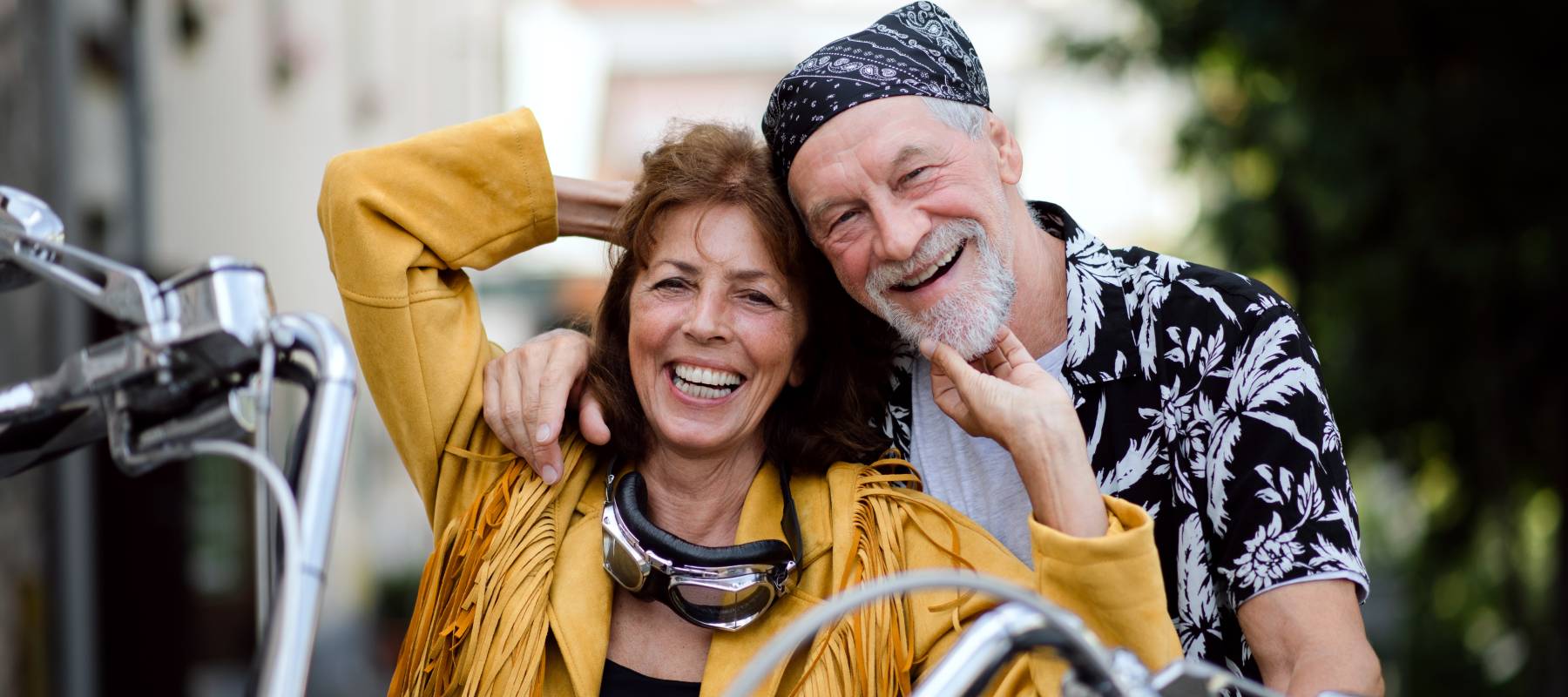 a senior Caucasian couple smiling with a motorbike