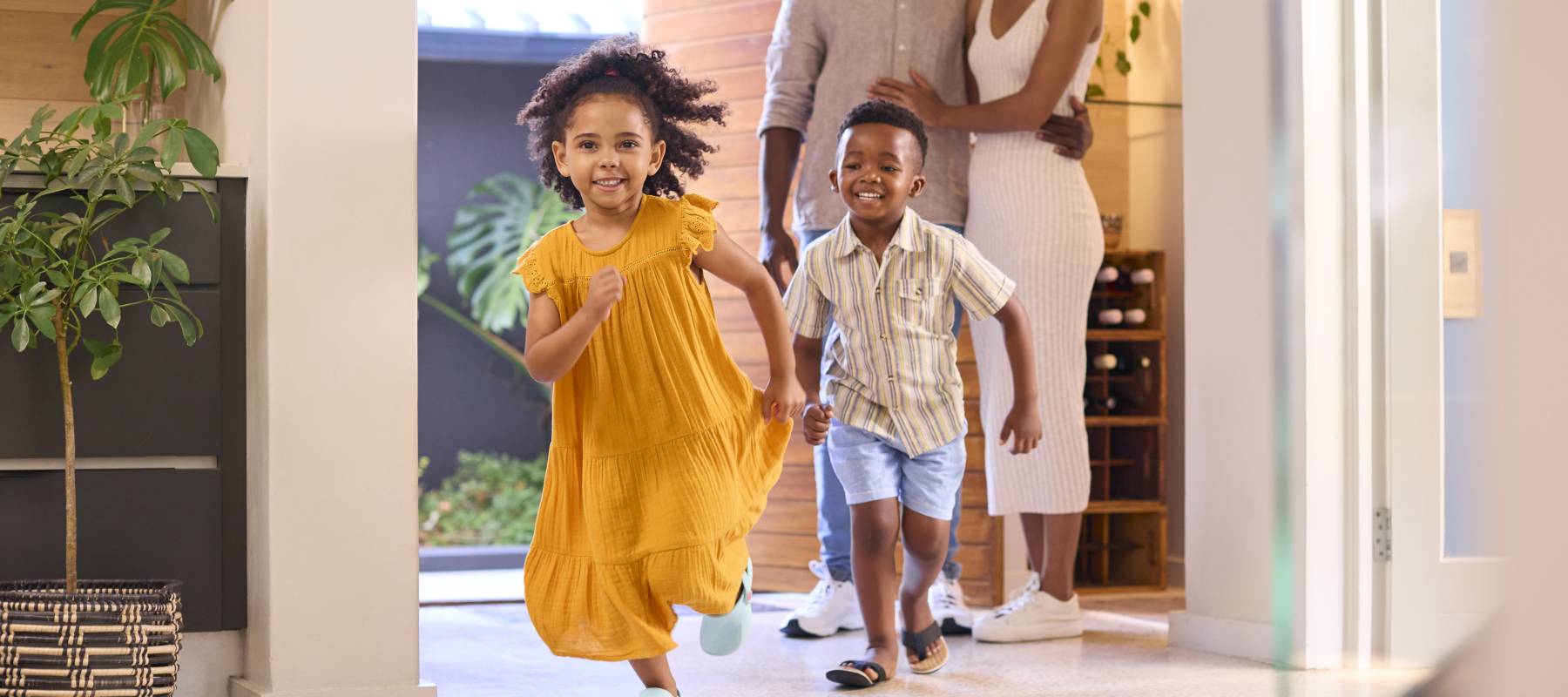 two young Black kids -- a girl and a boy -- running through their house