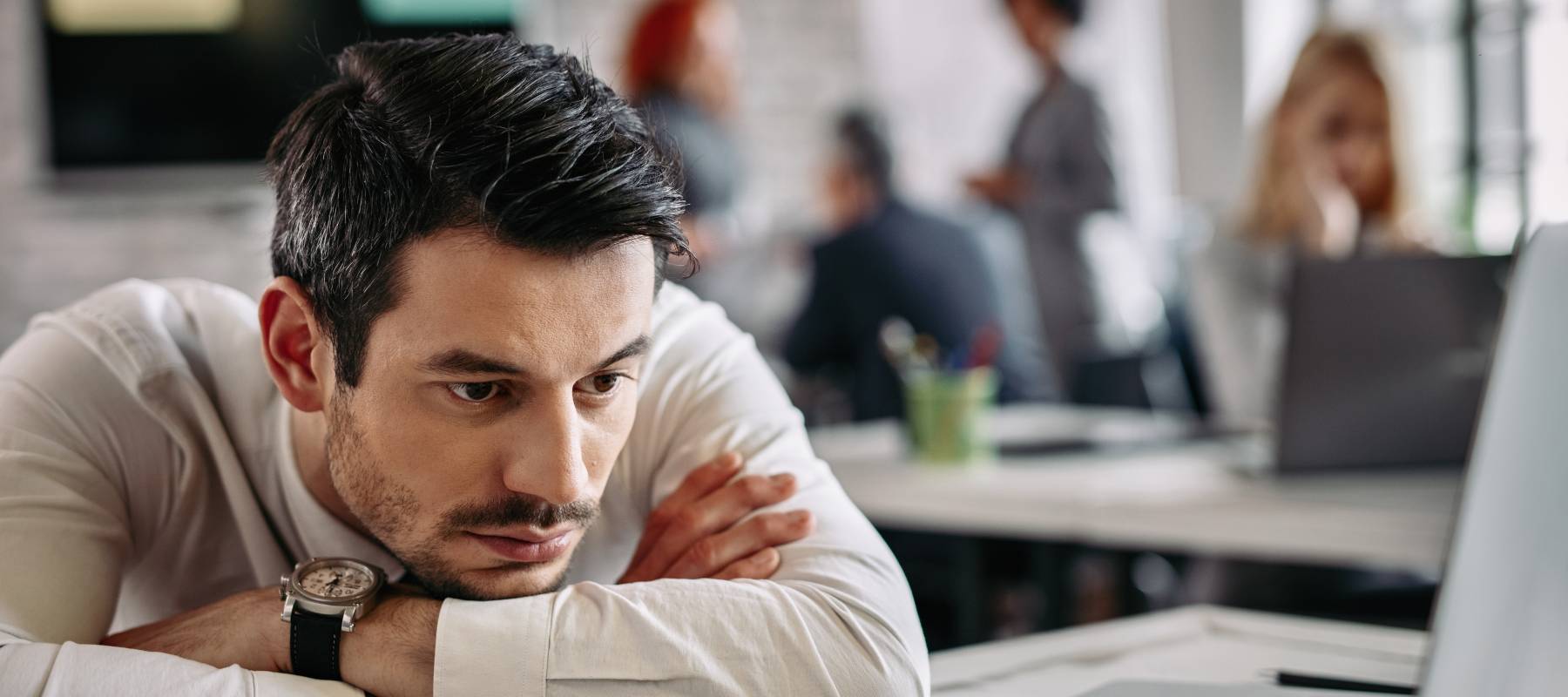Caucasian businessman feeling bored after working on laptop in the office