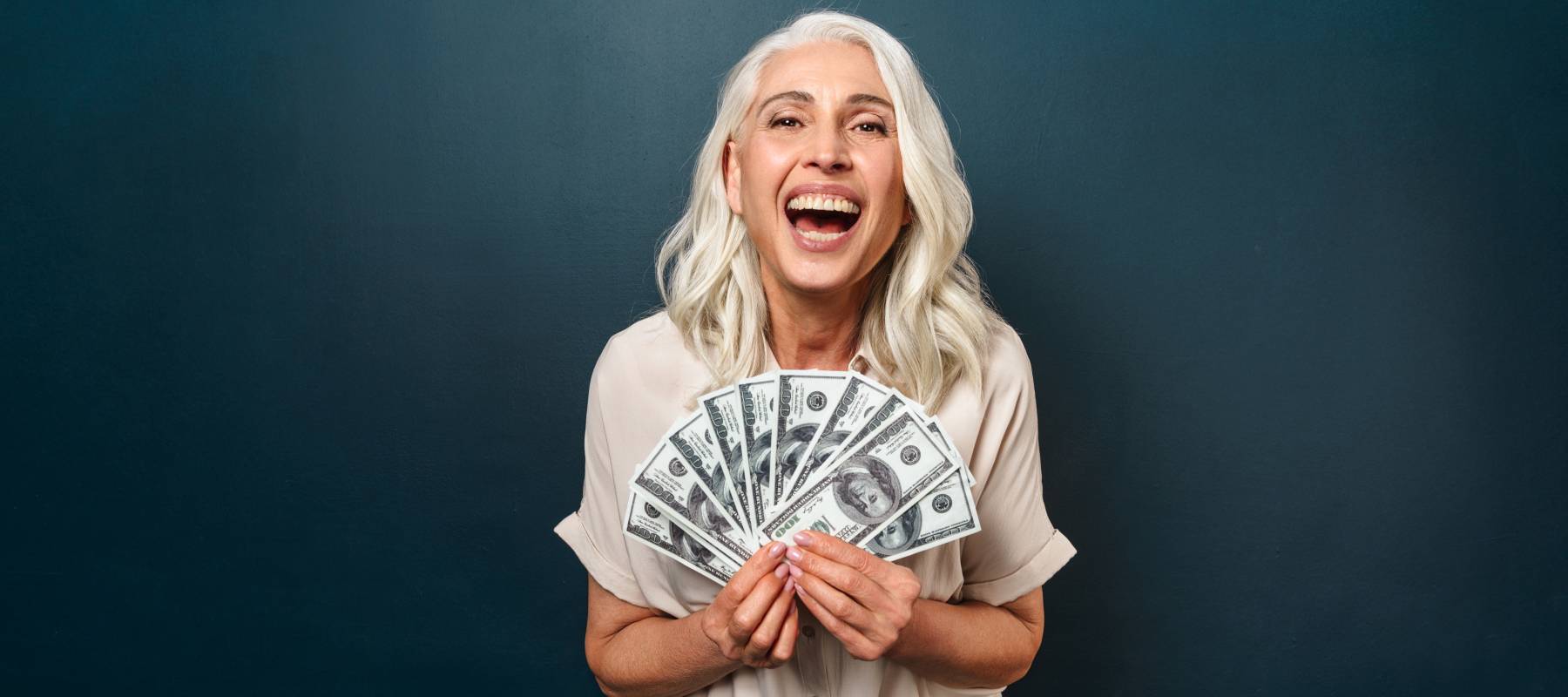 Woman holding fanned out cash in her hands black background