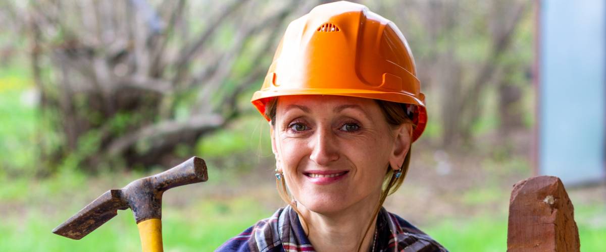 woman bricklayer behind a wall she's bricking
