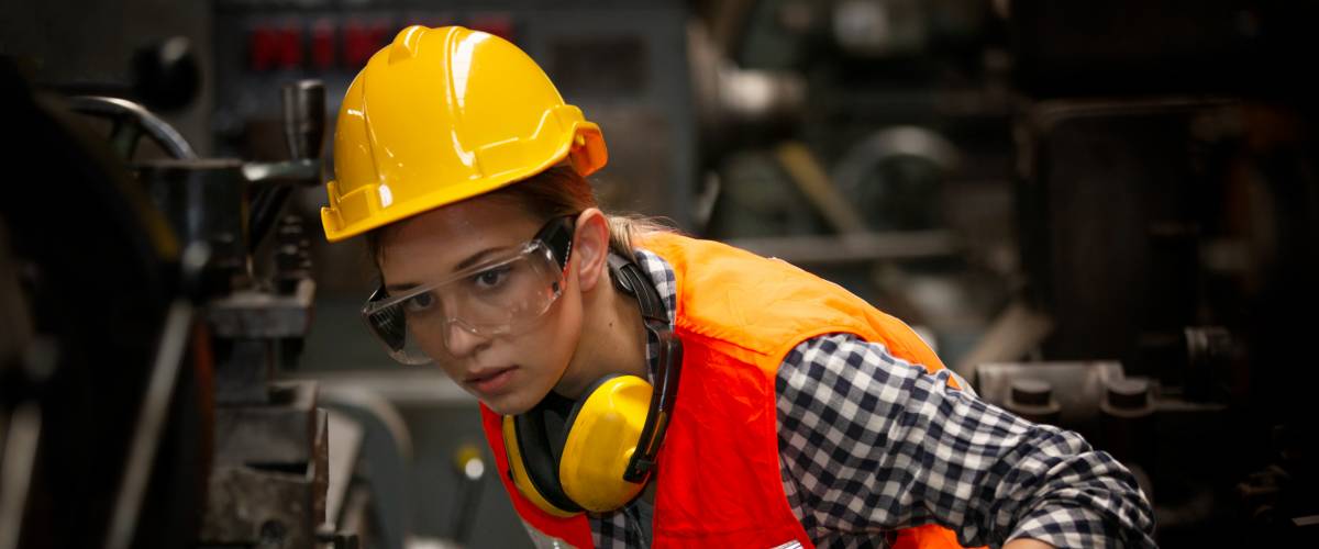 woman in a hard hat and safety vest working on an assembly line