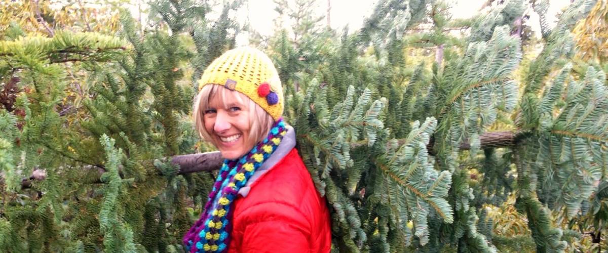 woman in a hard hat holding a chainsaw in front of some trees