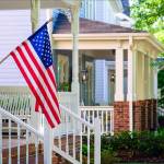A line of suburban homes display large American Flags