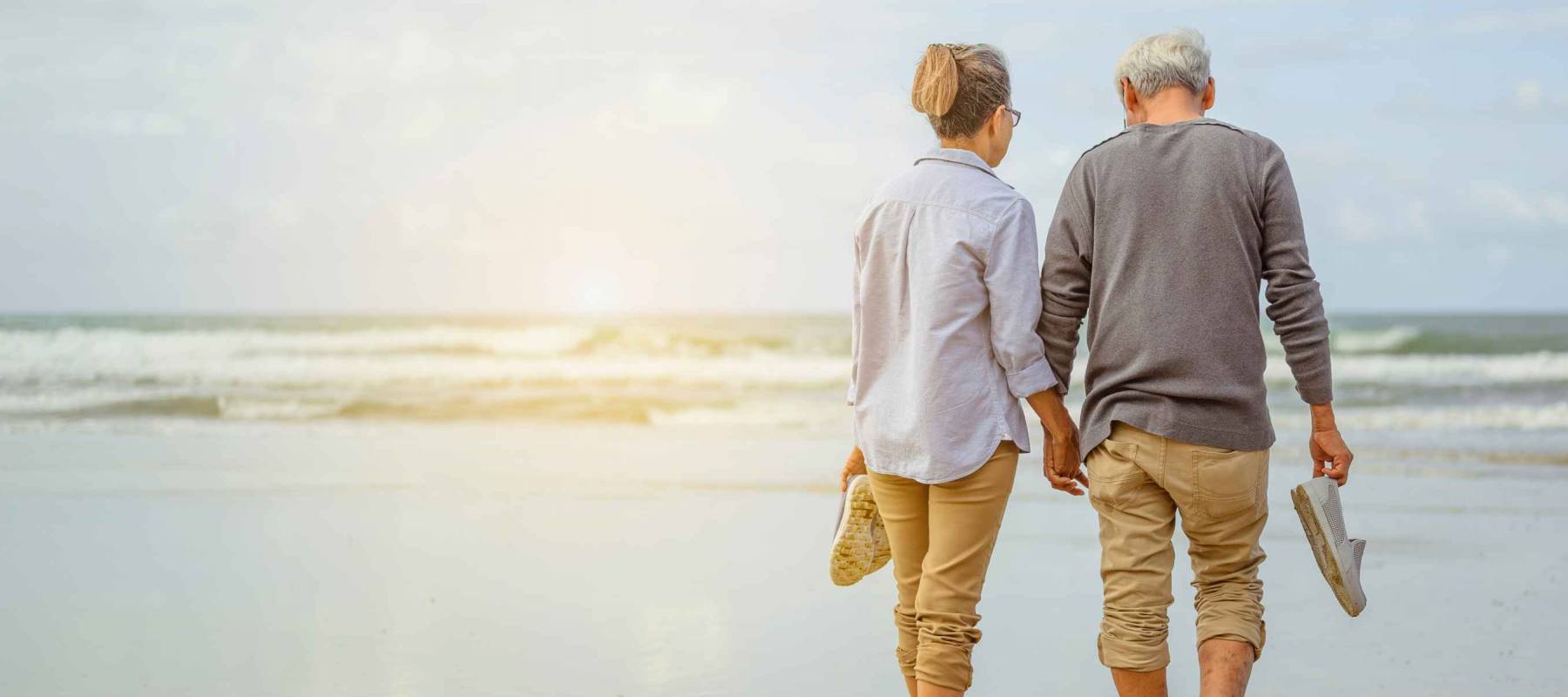 Senior couple walking on the beach holding hands