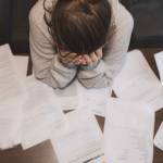 Midsection of tax auditor examining documents with magnifying glass at table in office