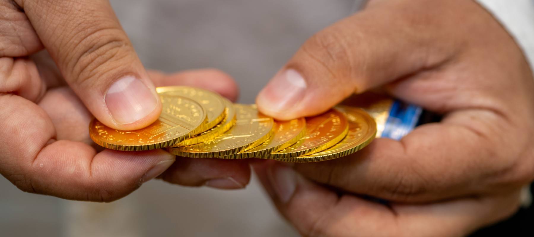 A closeup of hands holding gold coins.