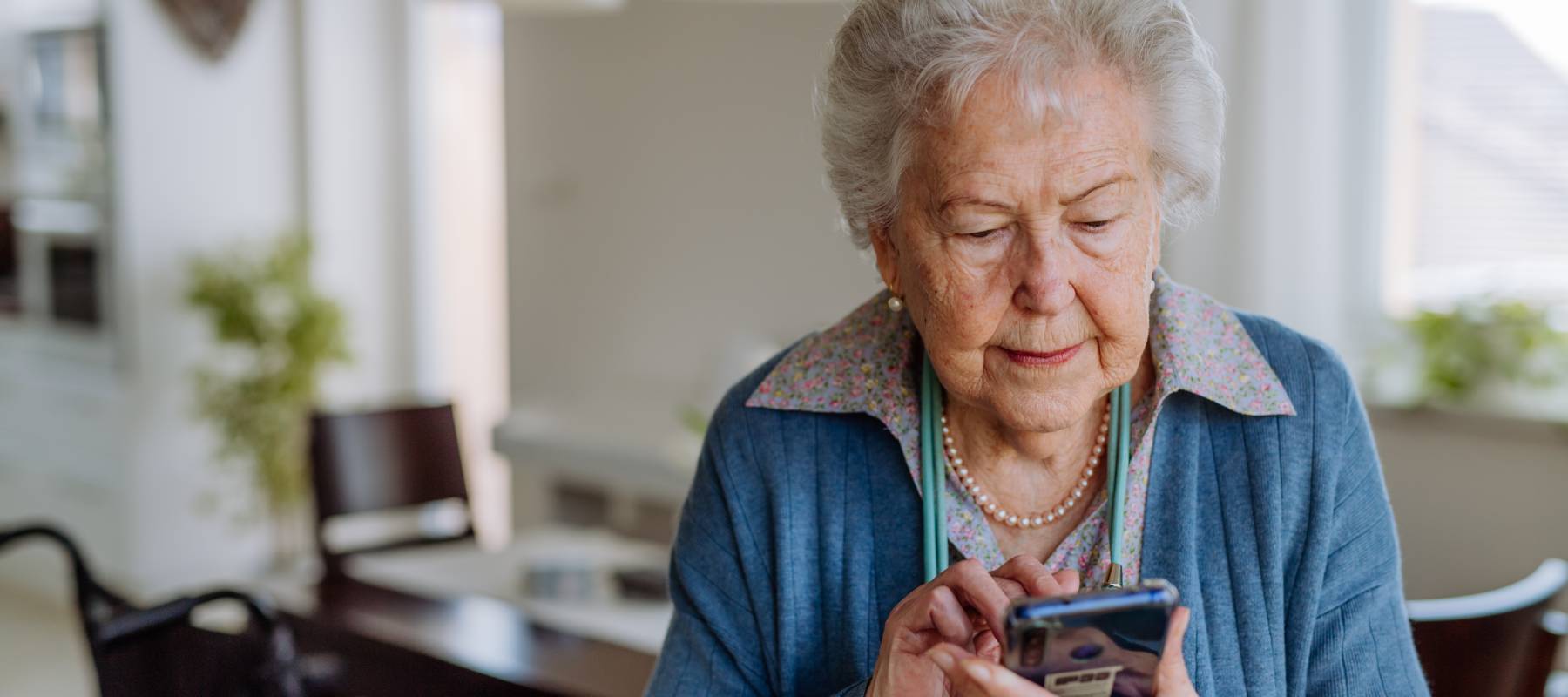 Older woman looks intently at benefits information on her phone.