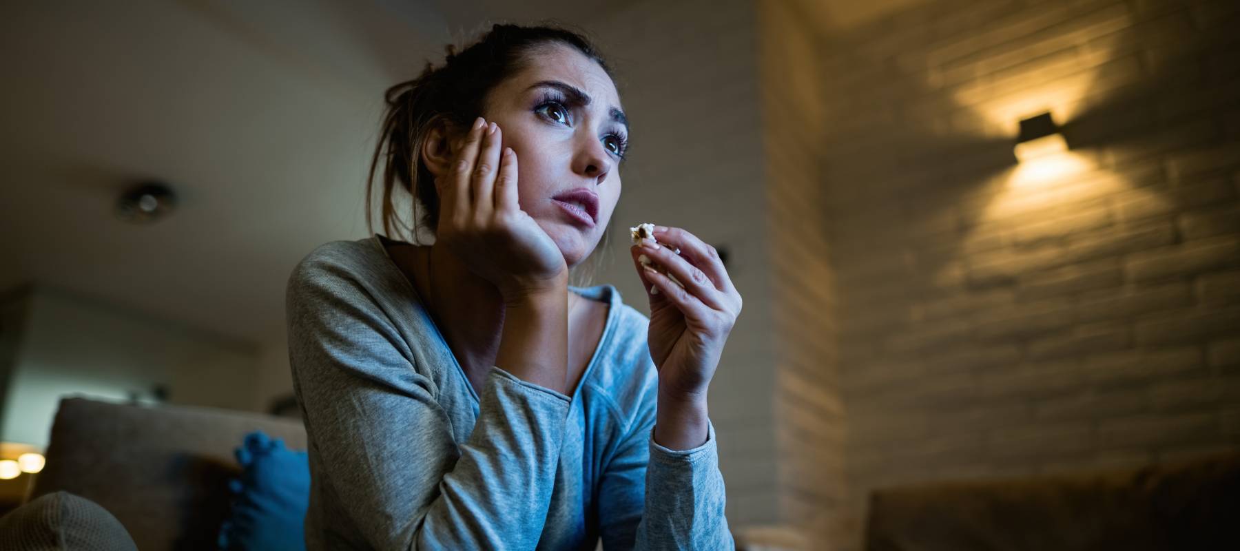 A distraught woman watching TV.