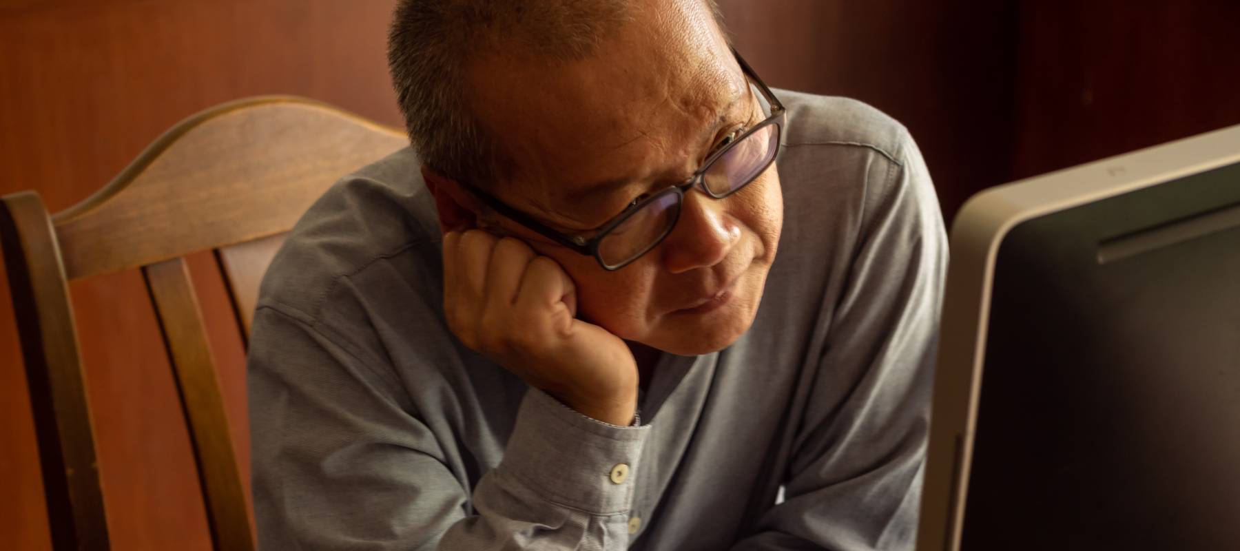 An older man stares at his computer monitor.