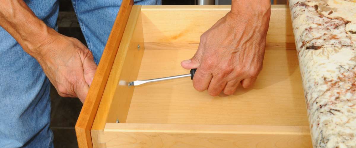 man installing new handle in drawer in kitchen