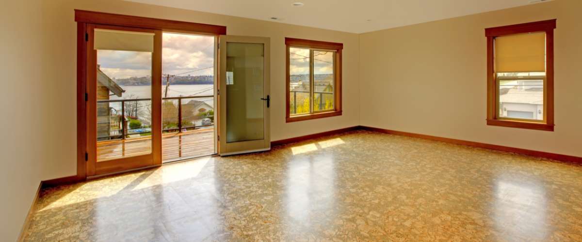 Large bright empty room with cork floor and balcony