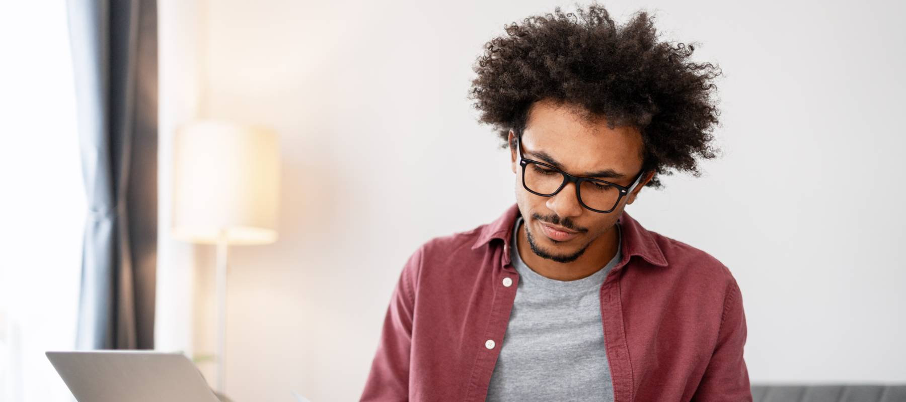 Bespectacled young man thoughtfully reviewing his finances.