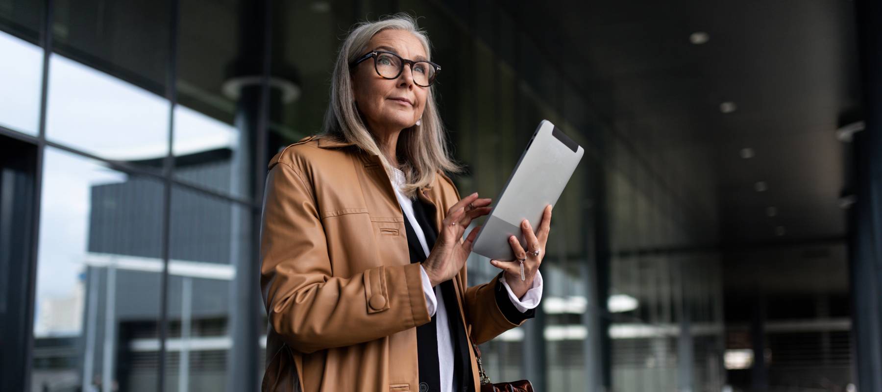 A thoughtful old woman stands with a tablet outside. RMDs may be the right option for you, depending on your mindset.