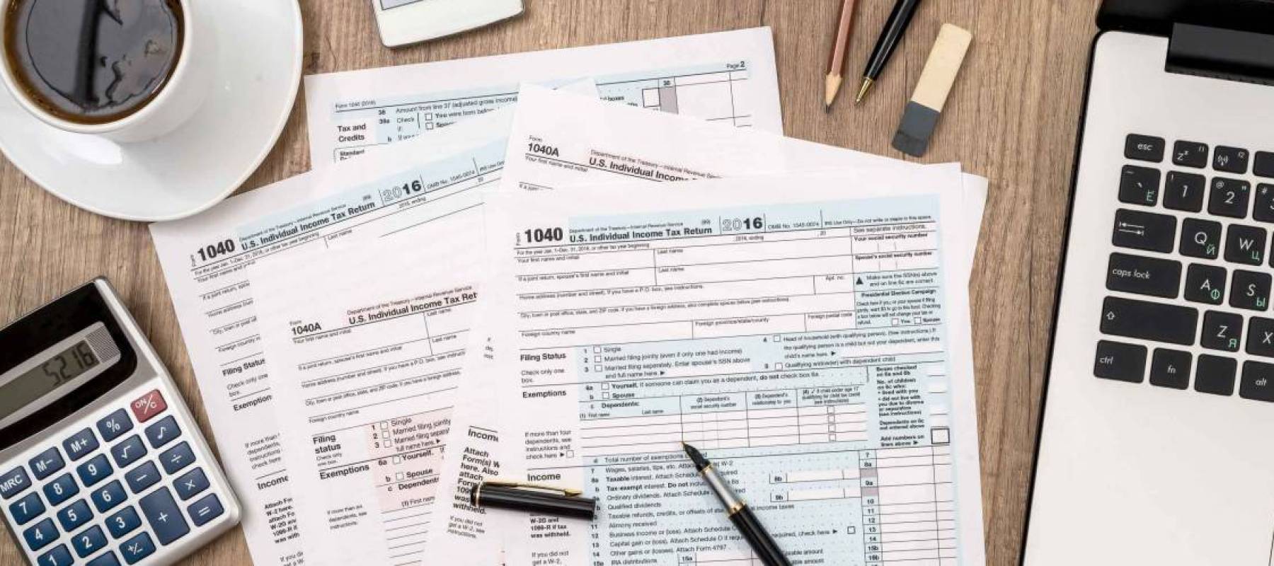 1040 tax form, laptop, glasses, coffee on desk
