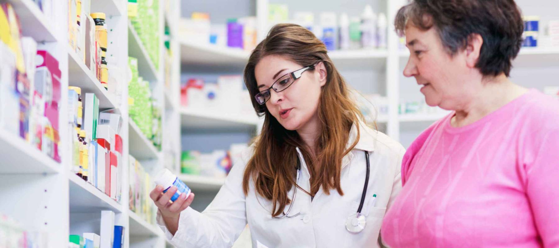 Female pharmacist discusses prescription medication with senior customer at pharmacy