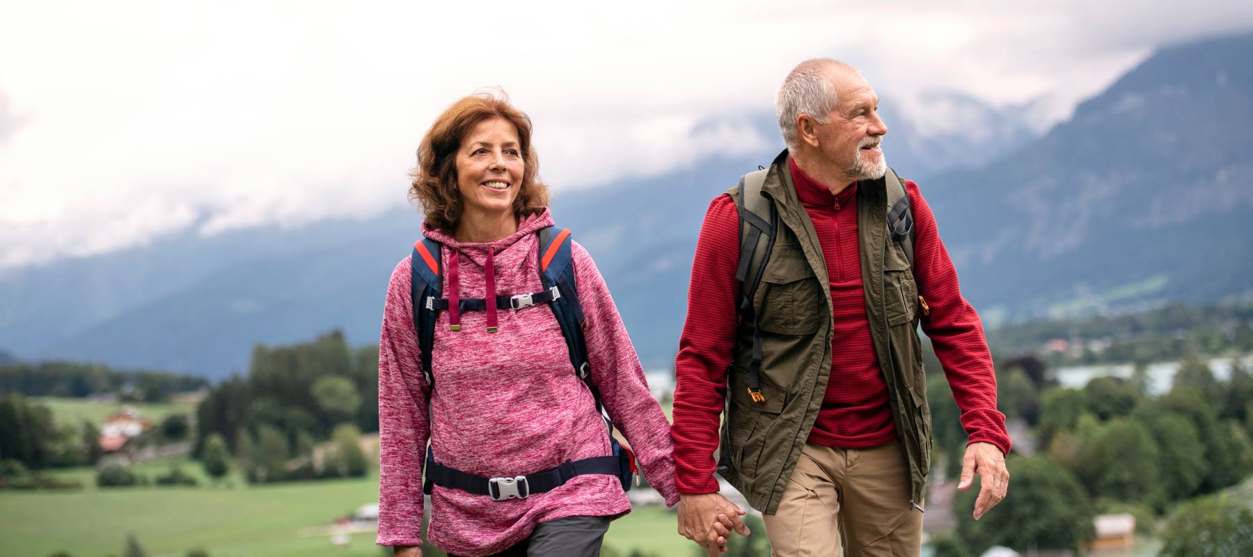 Relieved retired couple hiking while holding hands