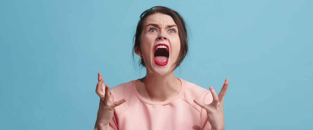 Screaming, hate, rage. Crying emotional angry woman screaming on blue studio background.