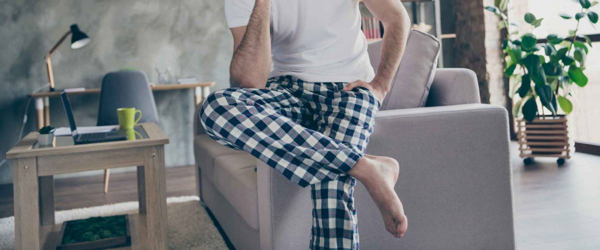 Photo of handsome man sit divan quarantine home call friend smartphone tell say talk speak lifestyle daily news wear checkered plaid pants trousers white t-shirt in house indoors